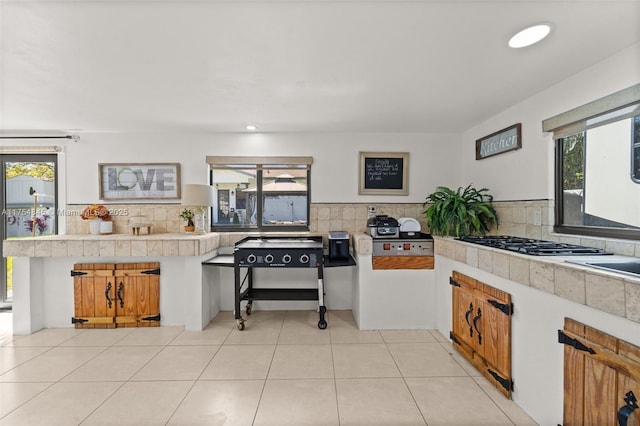 kitchen with light tile patterned floors, light countertops, decorative backsplash, and a healthy amount of sunlight