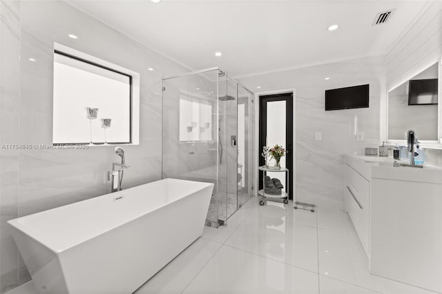 full bath with tile walls, visible vents, a stall shower, vanity, and a freestanding tub