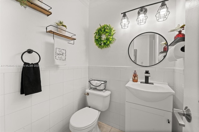 half bathroom featuring tile walls, wainscoting, vanity, and toilet