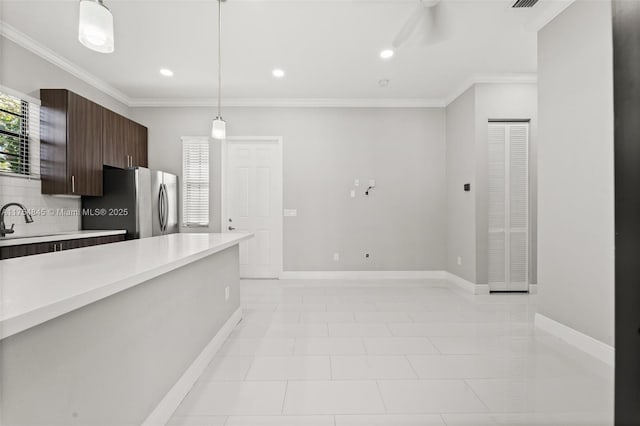 kitchen featuring dark brown cabinetry, baseboards, ornamental molding, freestanding refrigerator, and light countertops