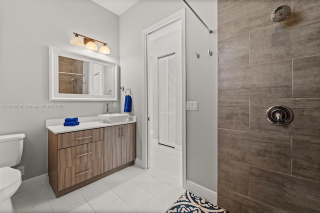 bathroom with baseboards, tiled shower, toilet, tile patterned flooring, and vanity