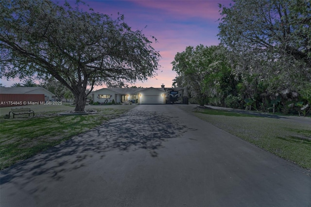 view of front of property with aphalt driveway, a front lawn, and an attached garage