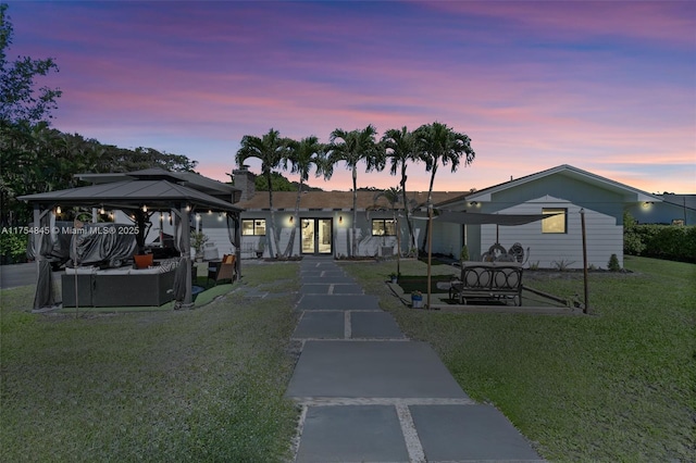 view of front facade featuring a gazebo, french doors, a lawn, and a patio