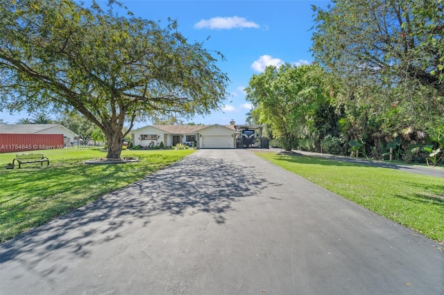 view of front facade with a garage, a front lawn, and aphalt driveway