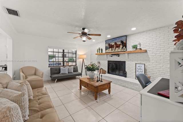 living room with a brick fireplace, visible vents, a textured ceiling, and light tile patterned flooring