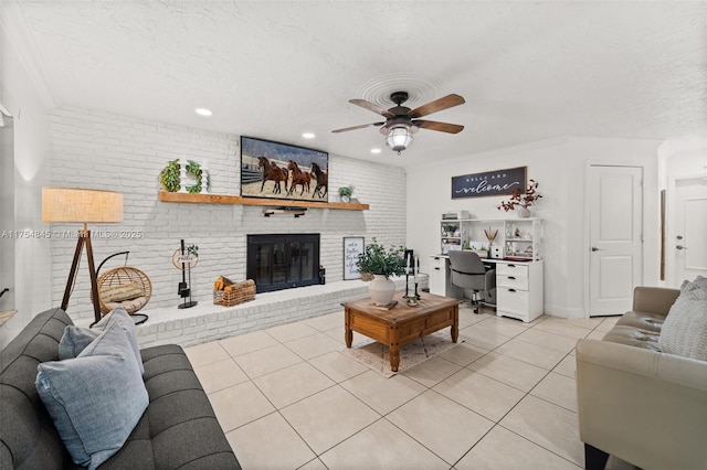 living area with light tile patterned floors, a textured ceiling, brick wall, a ceiling fan, and a brick fireplace