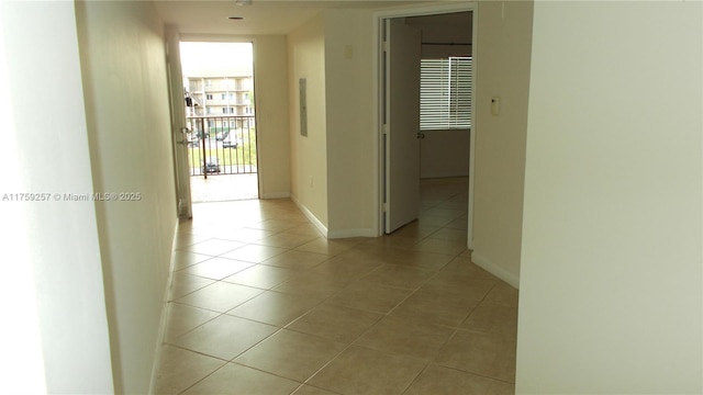 corridor featuring light tile patterned floors and baseboards