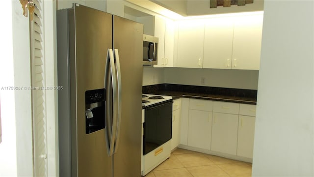 kitchen with dark countertops, white cabinetry, stainless steel appliances, and light tile patterned flooring