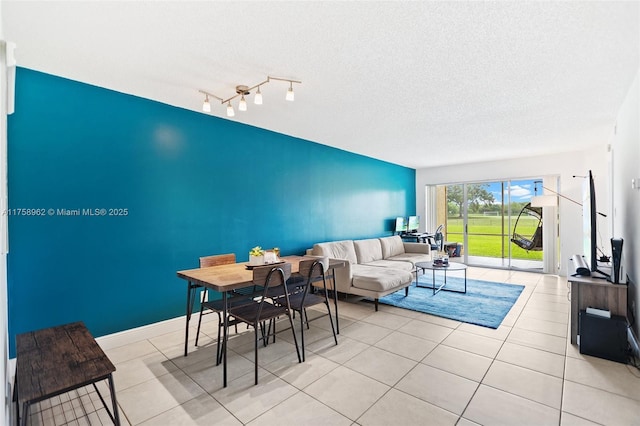 living area featuring light tile patterned floors, baseboards, and a textured ceiling