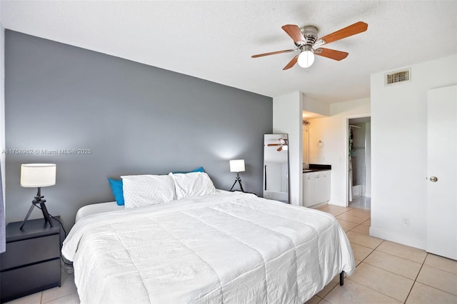 bedroom featuring light tile patterned floors, ensuite bathroom, a ceiling fan, visible vents, and baseboards