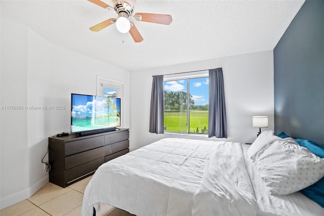 bedroom featuring light tile patterned floors, a textured ceiling, a ceiling fan, and baseboards