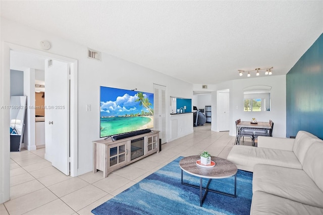 living room featuring rail lighting, visible vents, a textured ceiling, and light tile patterned flooring