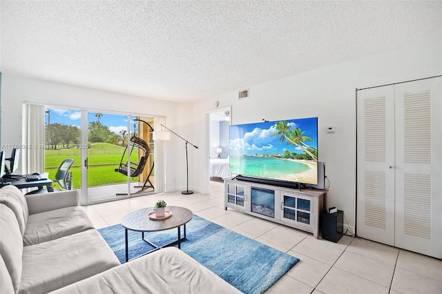 living area with tile patterned flooring, visible vents, and a textured ceiling