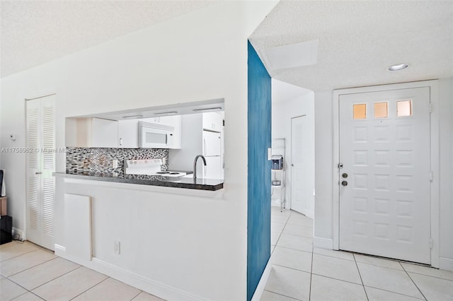 entryway with baseboards, a textured ceiling, and light tile patterned flooring