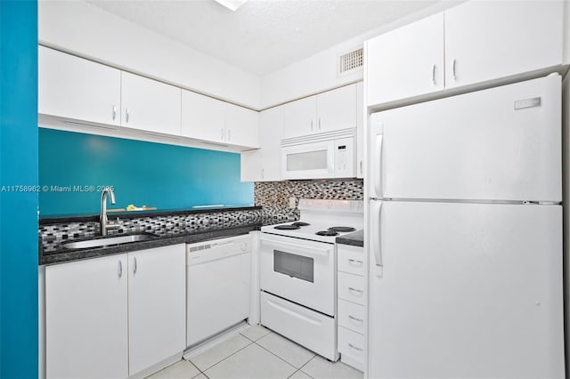 kitchen featuring white appliances, a sink, white cabinetry, backsplash, and dark countertops