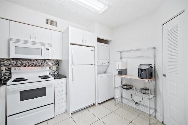 kitchen featuring white appliances, white cabinetry, visible vents, stacked washer / drying machine, and backsplash