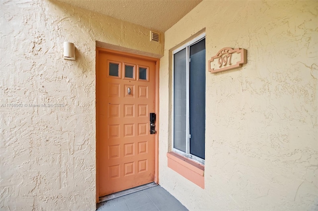 doorway to property with visible vents and stucco siding