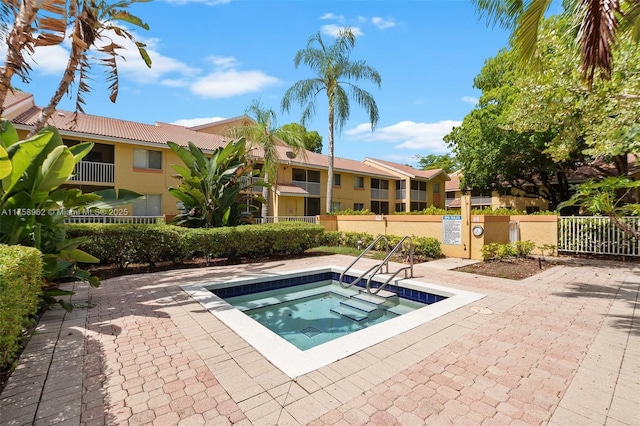 view of swimming pool with a community hot tub, fence, and a residential view