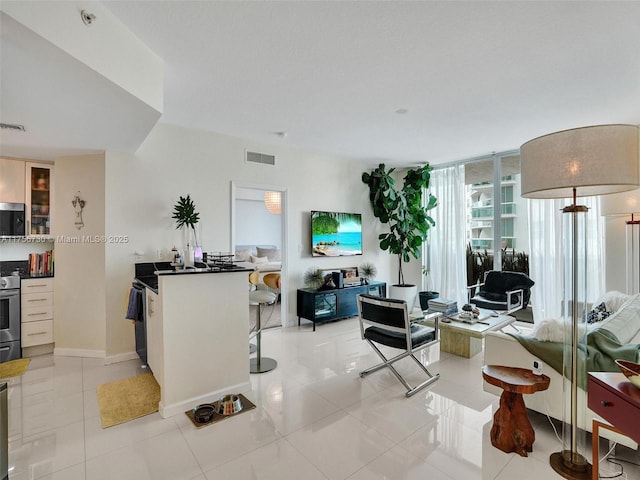 living area with light tile patterned floors, baseboards, and visible vents