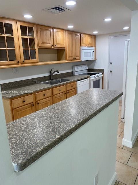 kitchen with light tile patterned floors, recessed lighting, white appliances, a sink, and visible vents