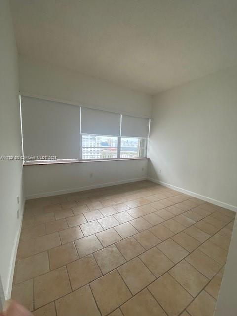 unfurnished room with tile patterned flooring and baseboards