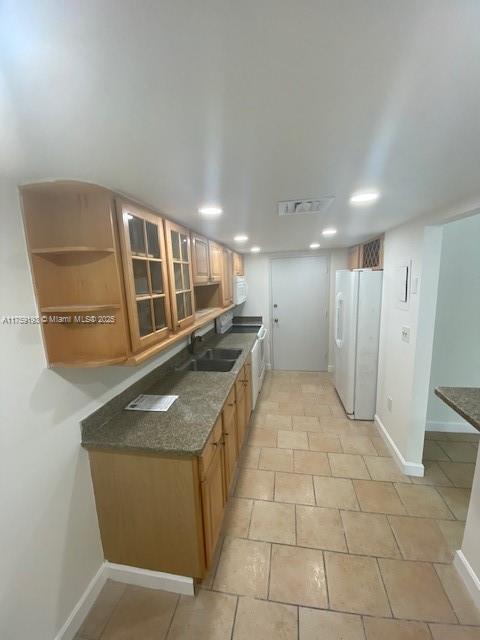 kitchen with white appliances, a sink, visible vents, and baseboards