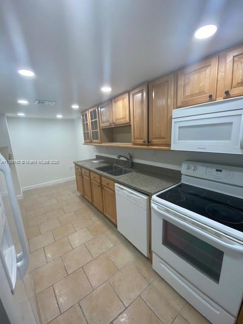 kitchen with baseboards, white appliances, a sink, and recessed lighting