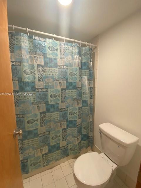 full bathroom with toilet, curtained shower, and tile patterned floors