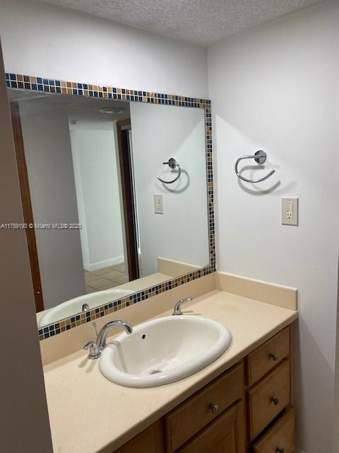 bathroom featuring a textured ceiling, tasteful backsplash, and vanity