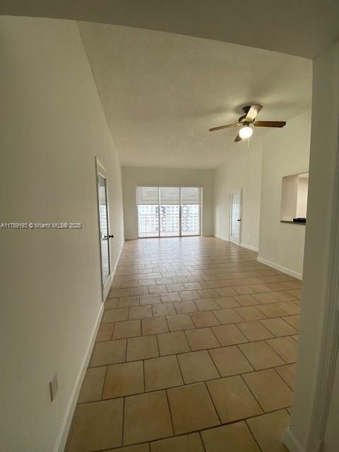 tiled spare room featuring ceiling fan and baseboards