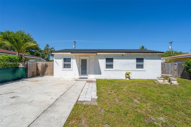 view of front facade featuring stucco siding, a front yard, and fence