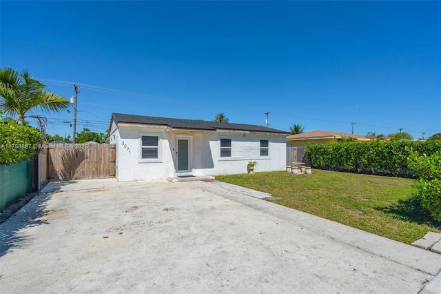 view of front of property with a front lawn, fence, and stucco siding