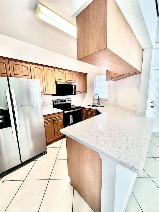 kitchen featuring light tile patterned floors, appliances with stainless steel finishes, light stone counters, a peninsula, and a sink