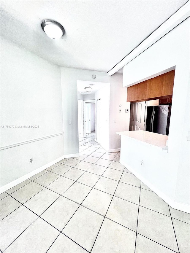 spare room with baseboards and light tile patterned floors