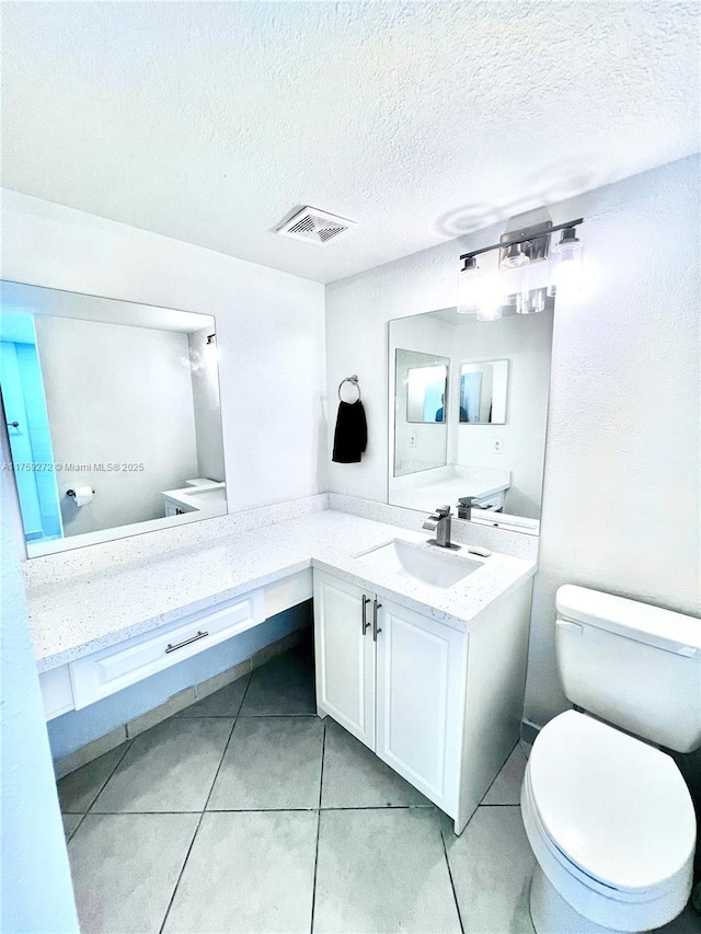 bathroom with visible vents, toilet, tile patterned flooring, a textured ceiling, and vanity