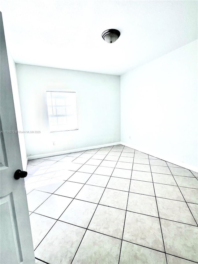 empty room with light tile patterned flooring and baseboards