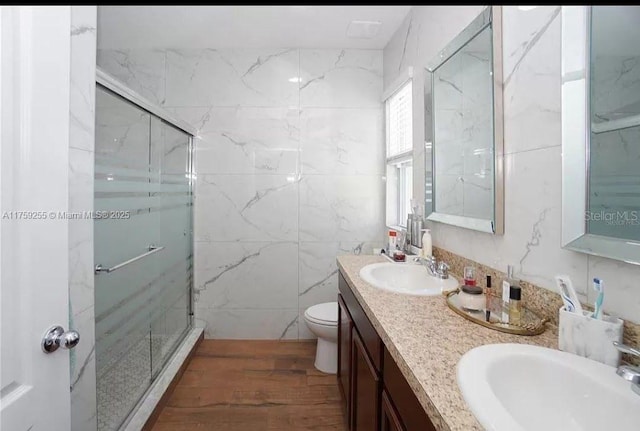 full bath with toilet, a sink, a marble finish shower, and double vanity