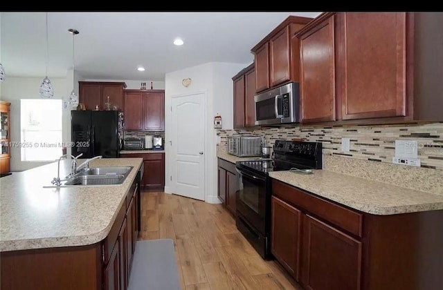 kitchen with light wood-style flooring, a sink, light countertops, black appliances, and tasteful backsplash