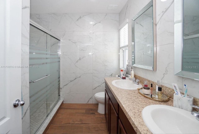 full bathroom with toilet, a sink, a marble finish shower, and wood finished floors