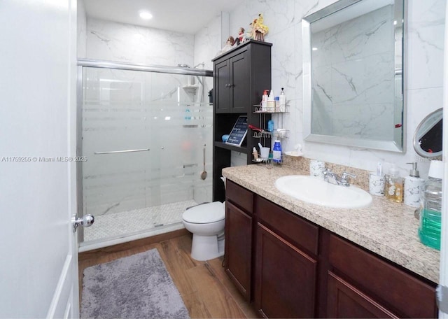 bathroom featuring toilet, a shower stall, vanity, and wood finished floors