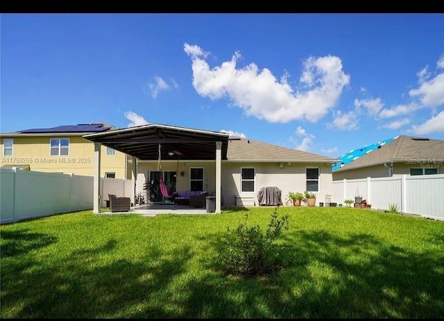 rear view of house featuring a yard, a patio area, a fenced backyard, and stucco siding