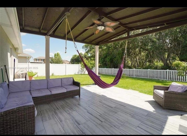 wooden deck featuring a fenced backyard, outdoor lounge area, a ceiling fan, and a yard