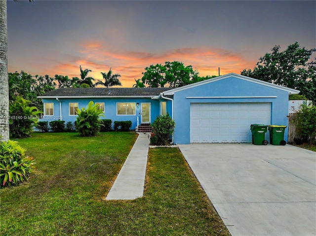 single story home featuring a garage, a yard, driveway, and stucco siding