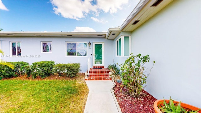 property entrance featuring a lawn and stucco siding