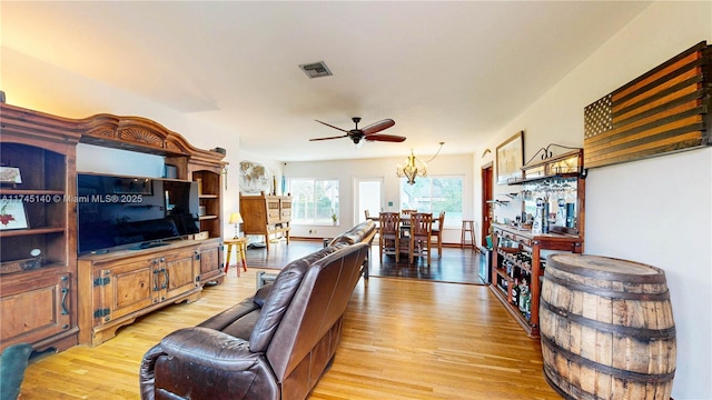 living room with light wood finished floors, baseboards, visible vents, and ceiling fan with notable chandelier