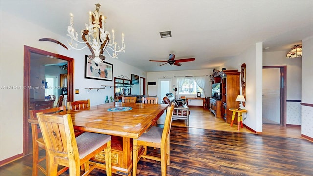 dining area featuring ceiling fan with notable chandelier, visible vents, baseboards, and wood finished floors