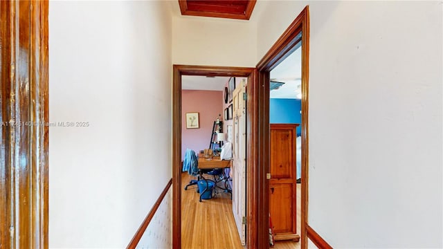 corridor with light wood finished floors and baseboards