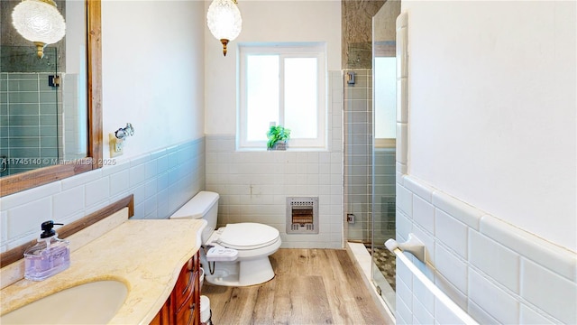 bathroom with a wainscoted wall, a stall shower, wood finished floors, and heating unit