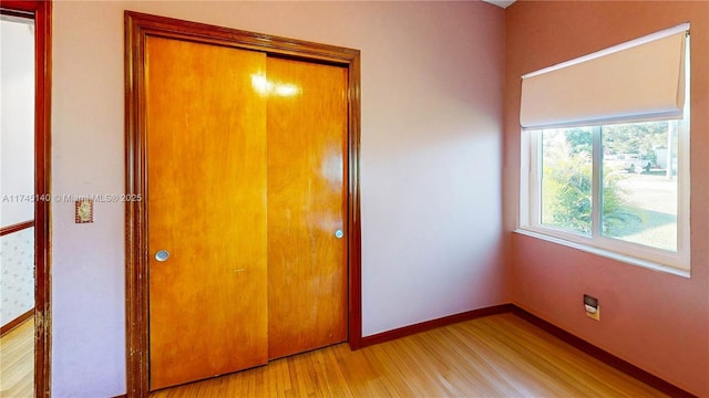 unfurnished bedroom with light wood-type flooring, baseboards, and a closet