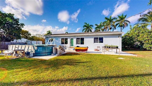 back of house featuring a patio area, an outdoor pool, a lawn, and stucco siding